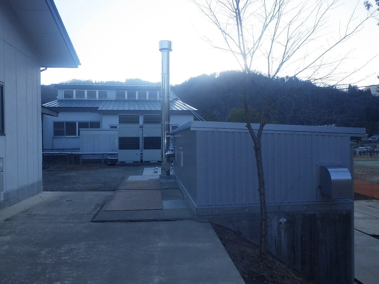 既存の建物の脇に並べて据えたボイラー室と煙突