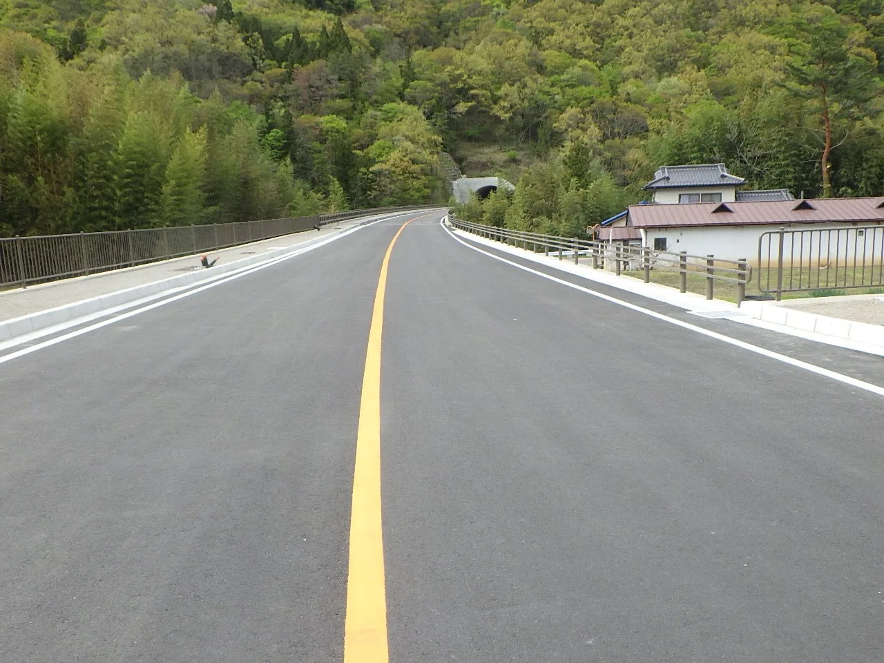 舗装を終えた2車線の道路。奥にトンネルの坑口が見える