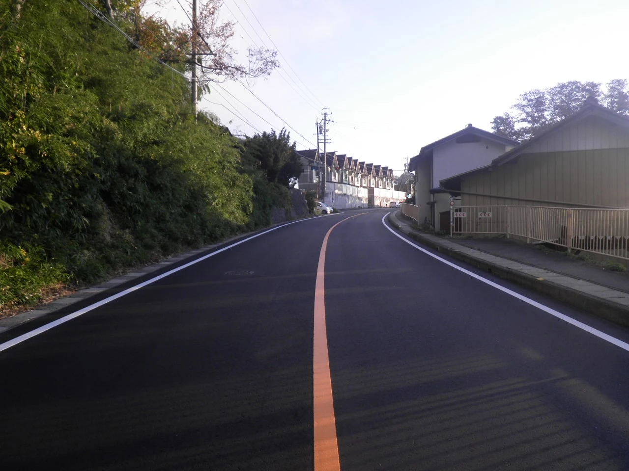 舗装を終えた坂道と、引いたばかりのオレンジ色の中央線