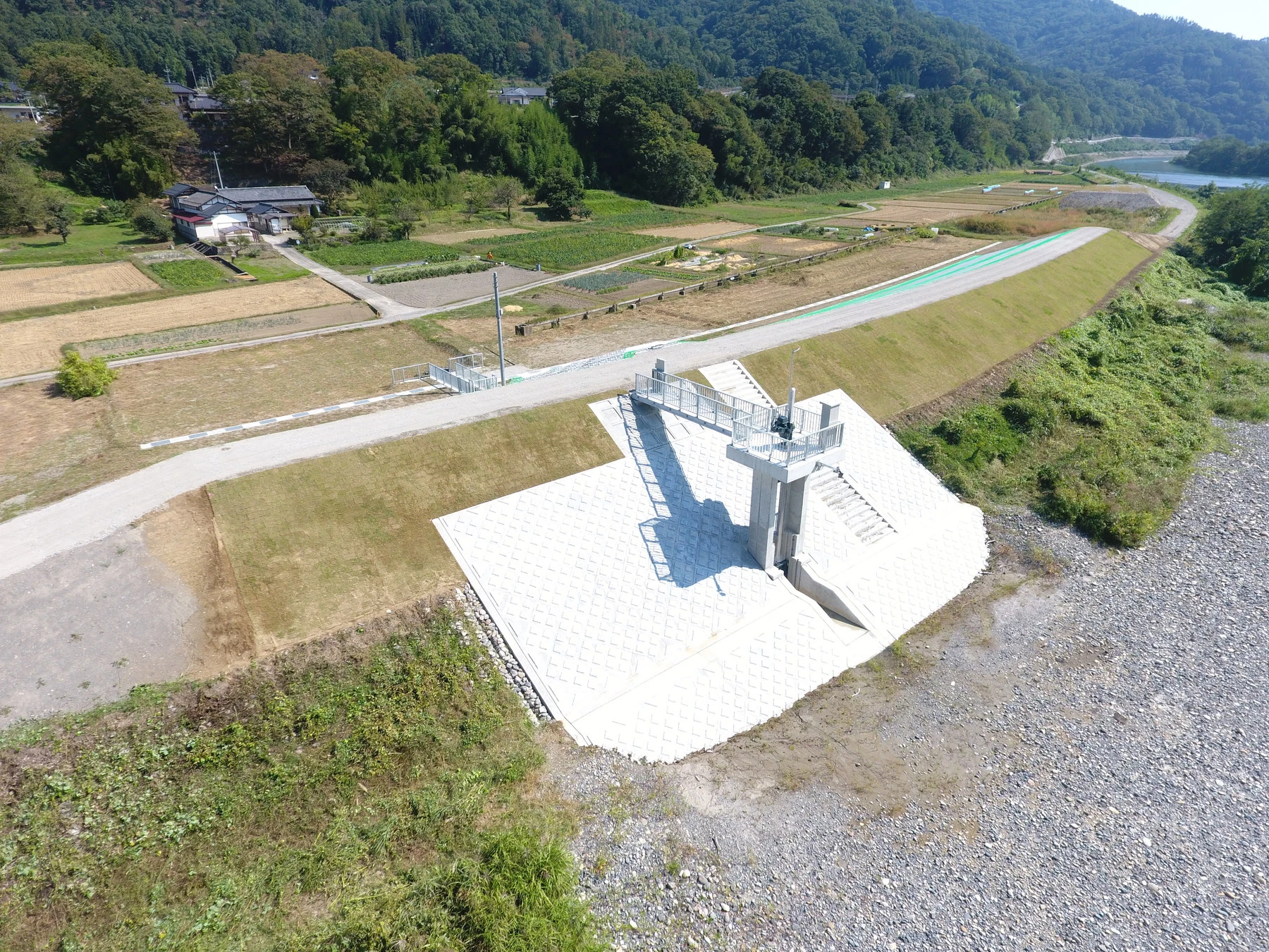 上空から見た、堤防に据えた樋門のゲートと、ブロックで覆った斜面