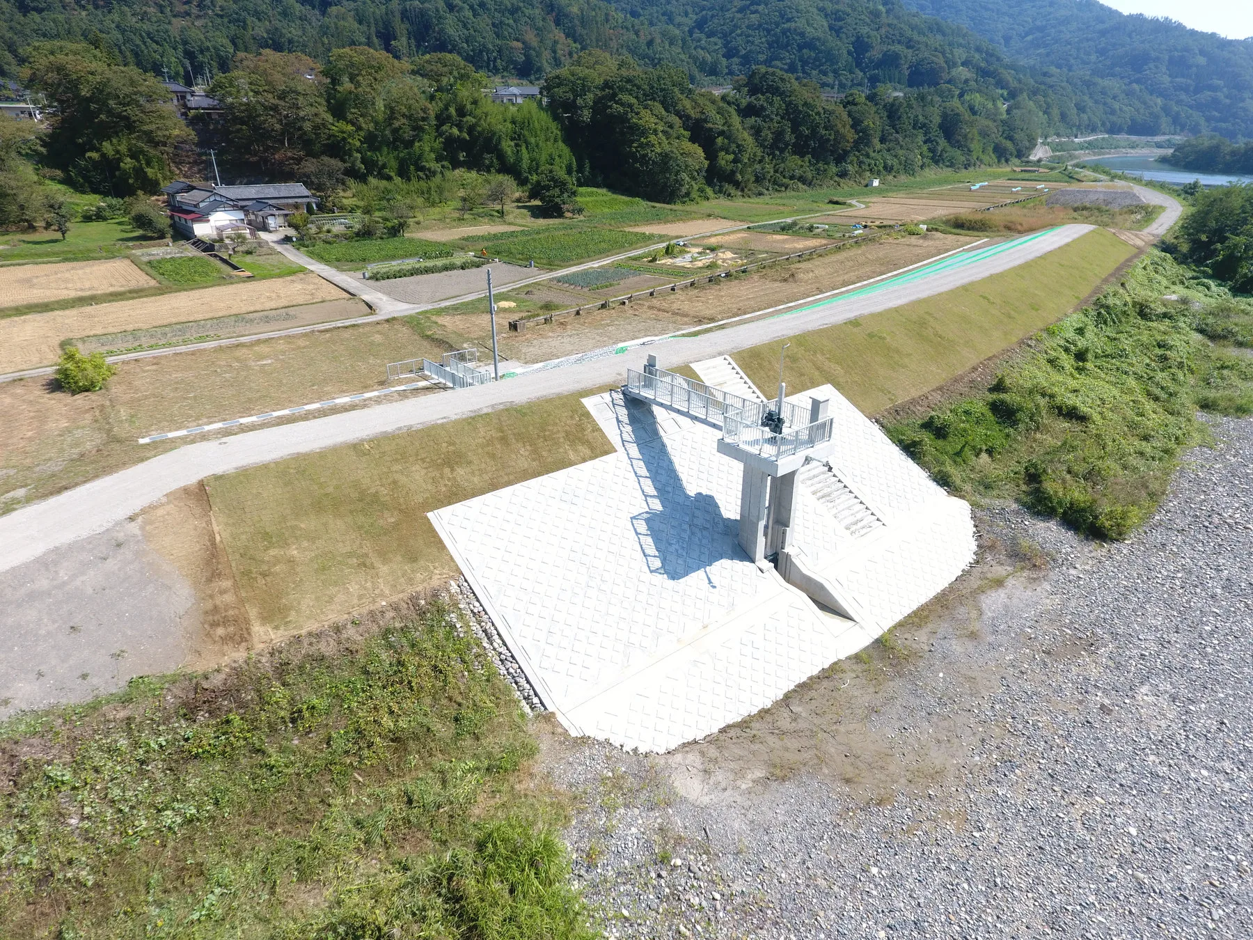 上空から見た、堤防に据えた樋門のゲートと、ブロックで覆った斜面