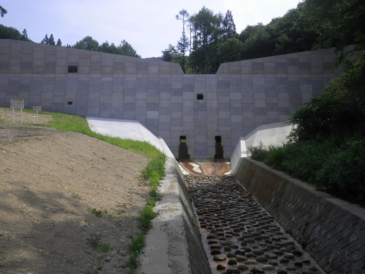 完成後、下流側から見た砂防堰堤の全景と、玉石を敷いた水路