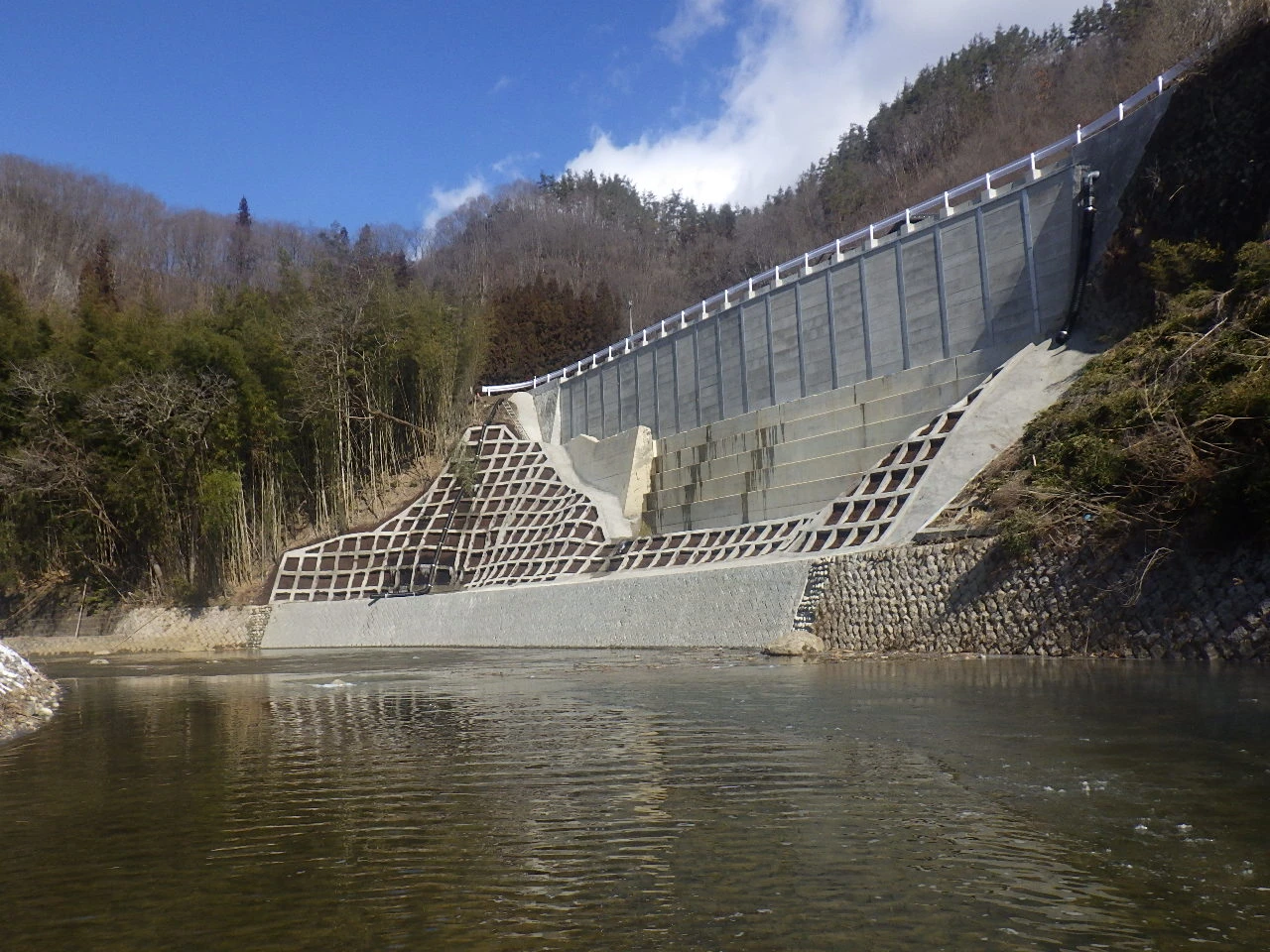 川面の高さから見上げた完成後の護岸。ブロック張りの斜面と、裾を固めたコンクリート