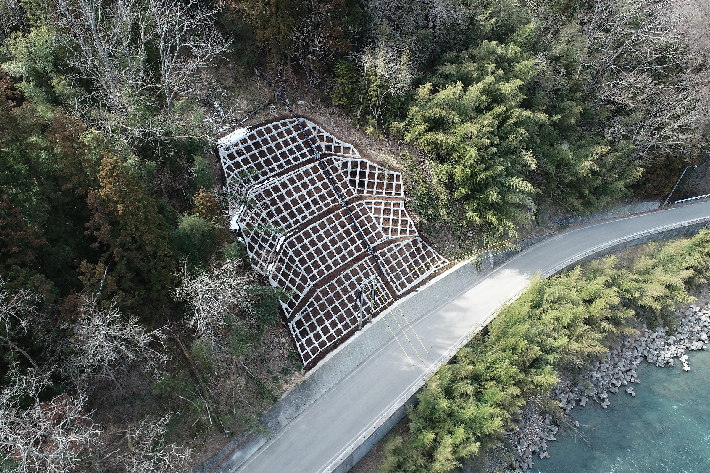 法枠工で覆われた斜面と、ふもとを通る道路を上空から見た様子