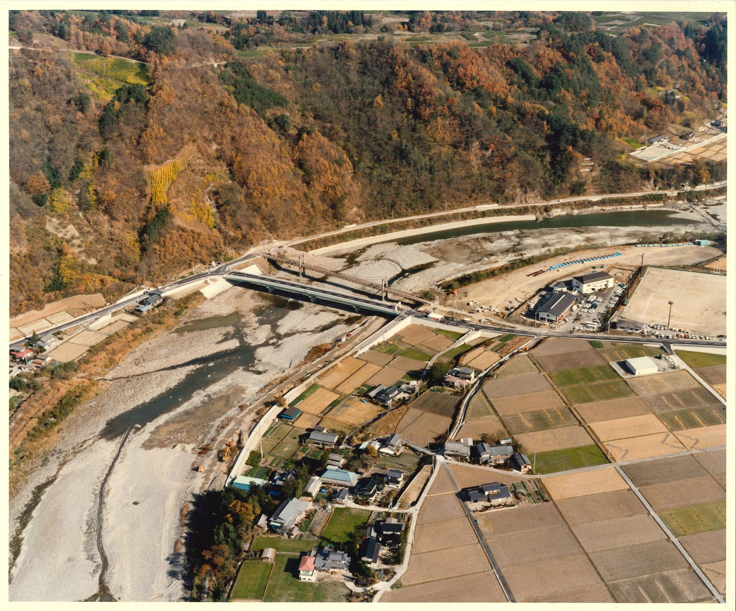 上空から見た、川沿いの集落と造成された土地（秋）