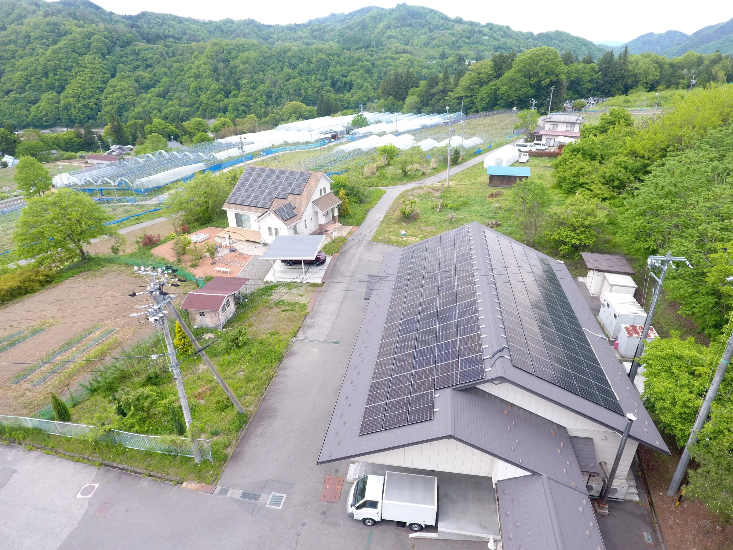 大きな切妻屋根の一面に並ぶ太陽光パネルと、背後の山