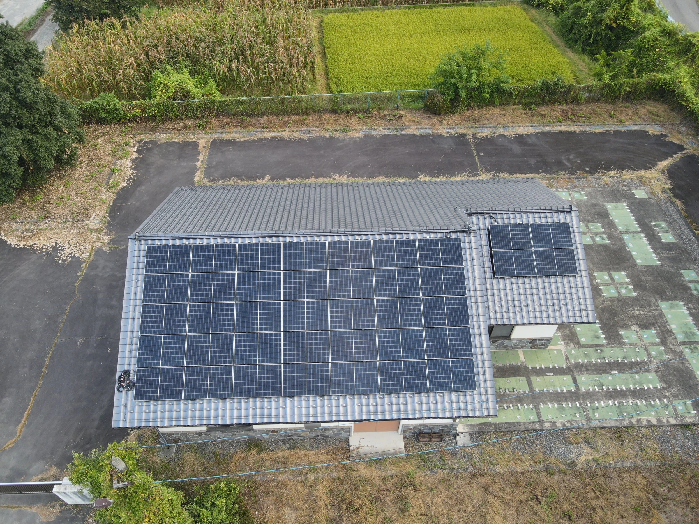 大きな屋根の一面いっぱいに並ぶ太陽光パネルと、隣の処理施設