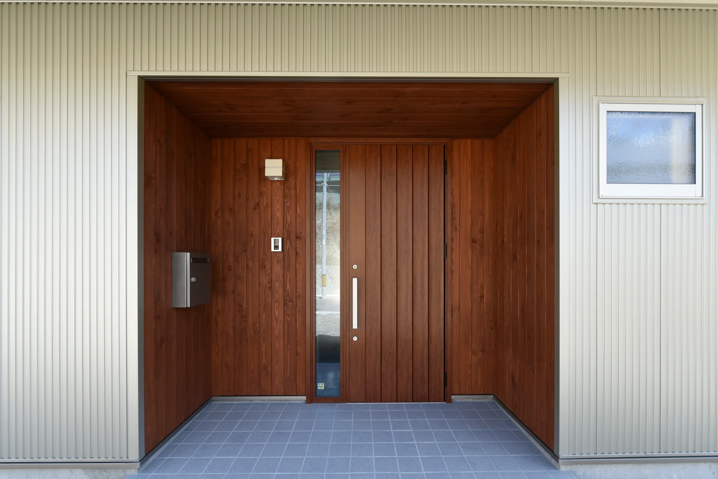 完成した住宅の玄関まわり。木目の扉と白い外壁